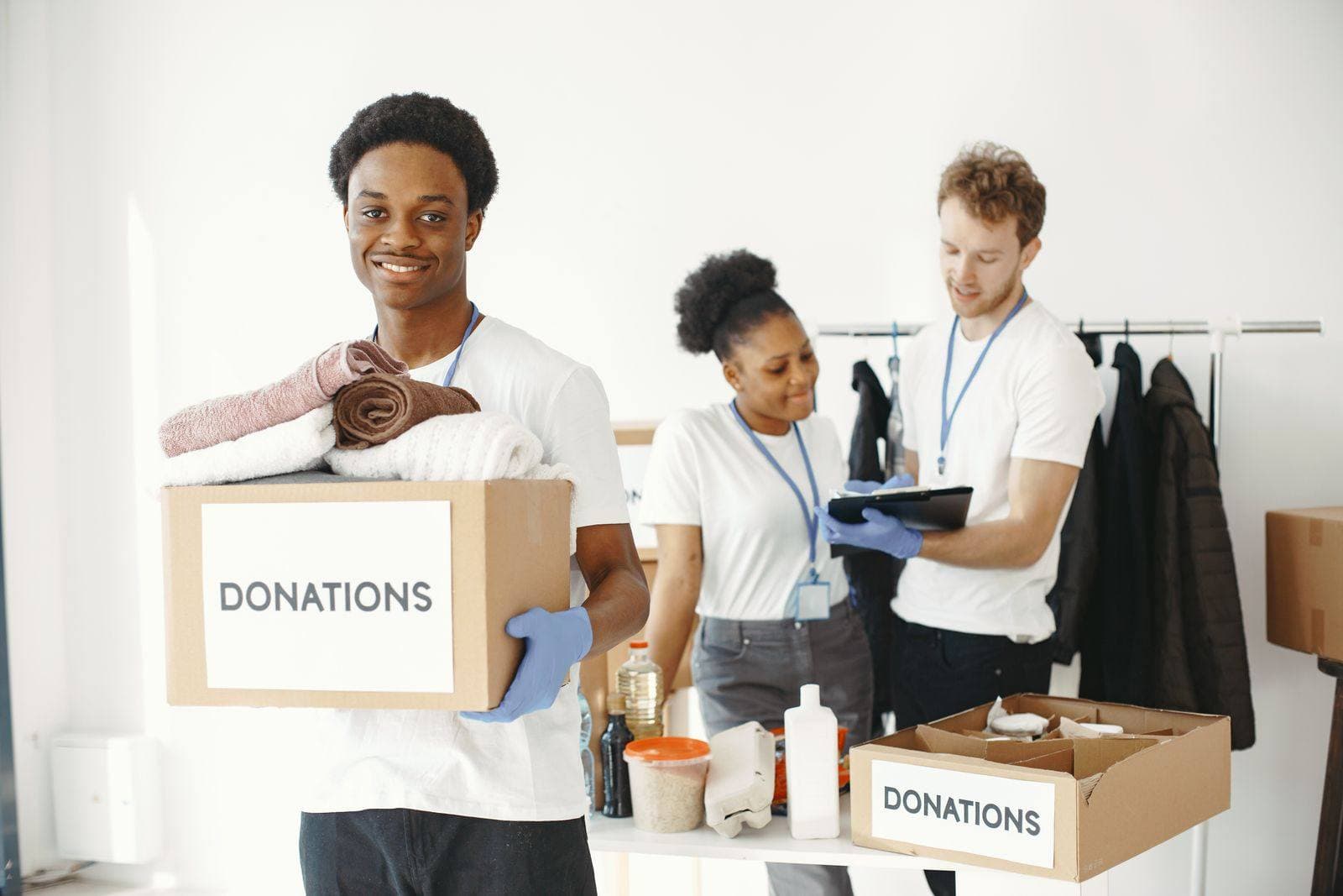 A smiling volunteer carries a donations box stacked with folded towels
